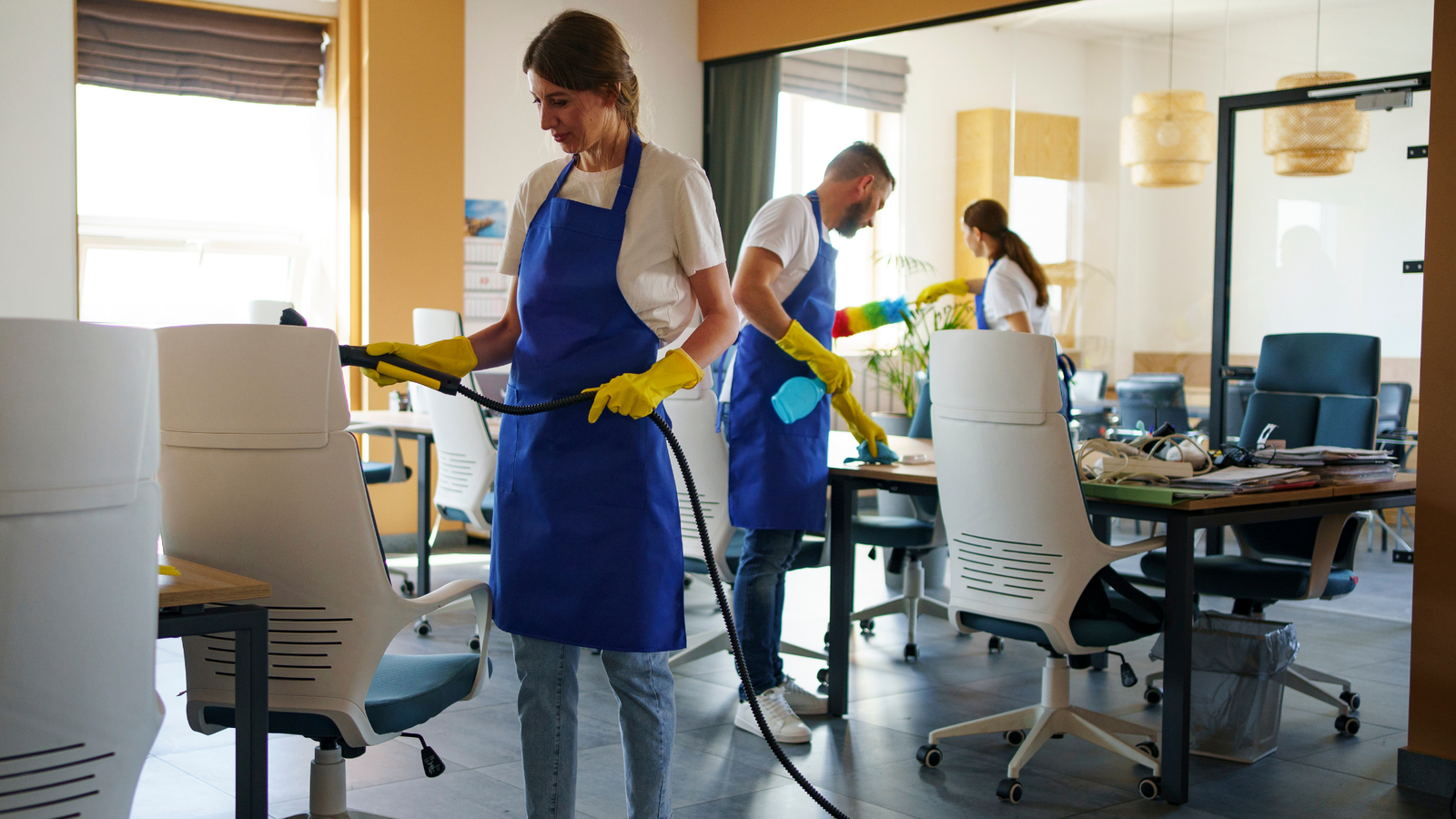 Three professional cleaners performing office cleaning as part of expert cleaning services.
